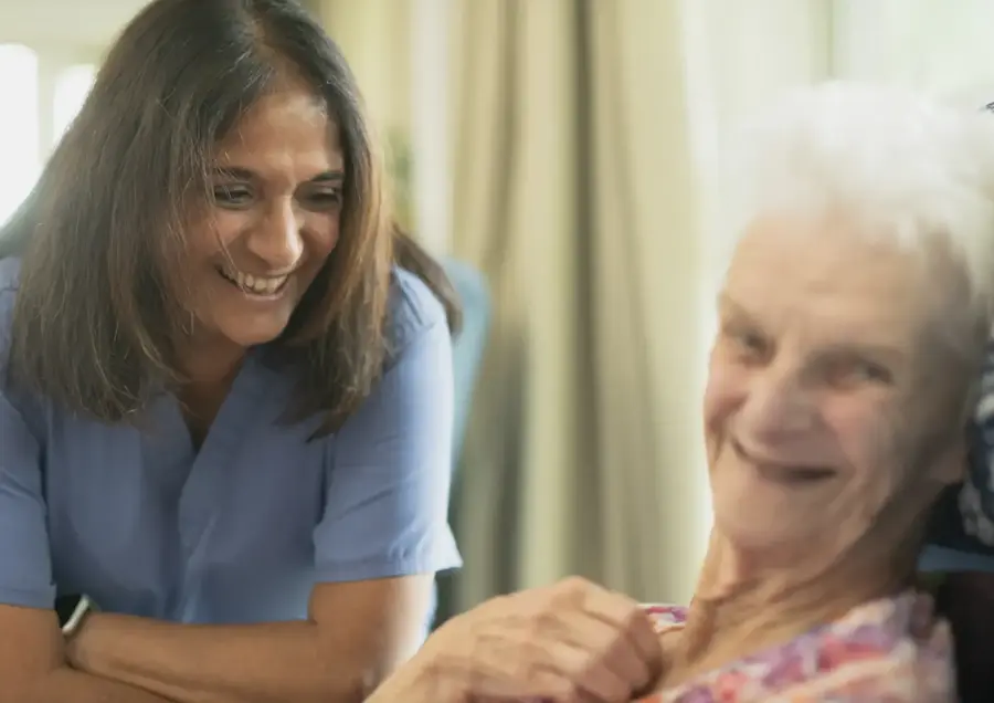 A caregiver laughing with an elderly woman in her home